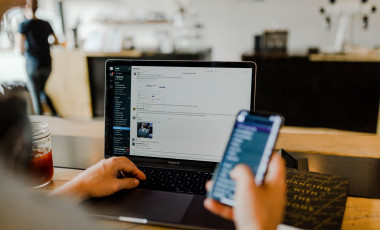 Developer working on laptop while browsing through mobile version of the site. Credit: Austin Distel/Unsplash